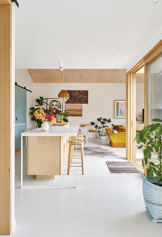 Plywood kitchen with white kitchen island and pops of pastel colour. 